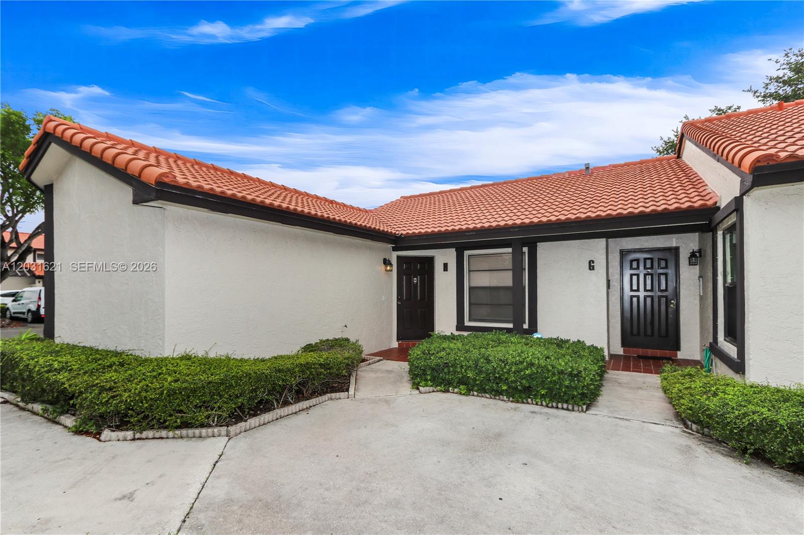 The exterior of a single-story home features white stucco walls, a red tile roof, and two dark doors — 15240 SW 45th Ter # H, Miami FL 33185, MIAMI, FL