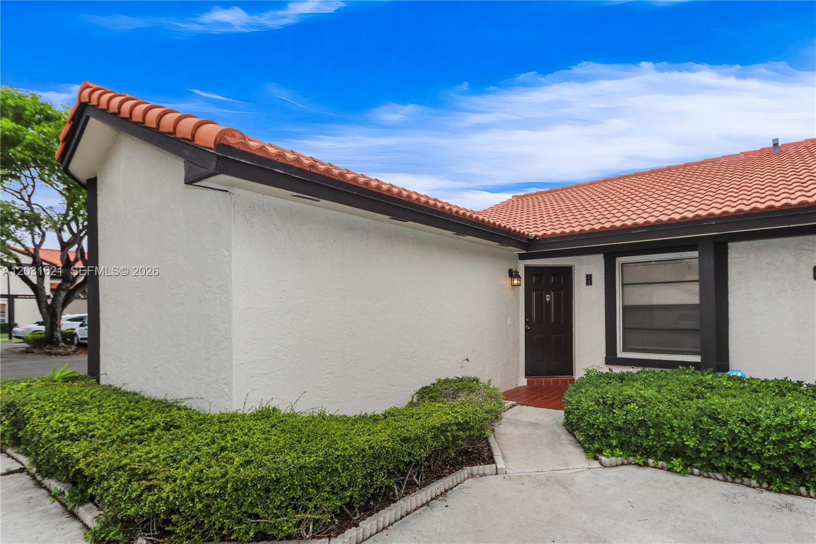 The exterior of a single-story home features a tiled roof, white stucco walls, and landscaping — 15240 SW 45th Ter # H, Miami FL 33185, MIAMI, FL