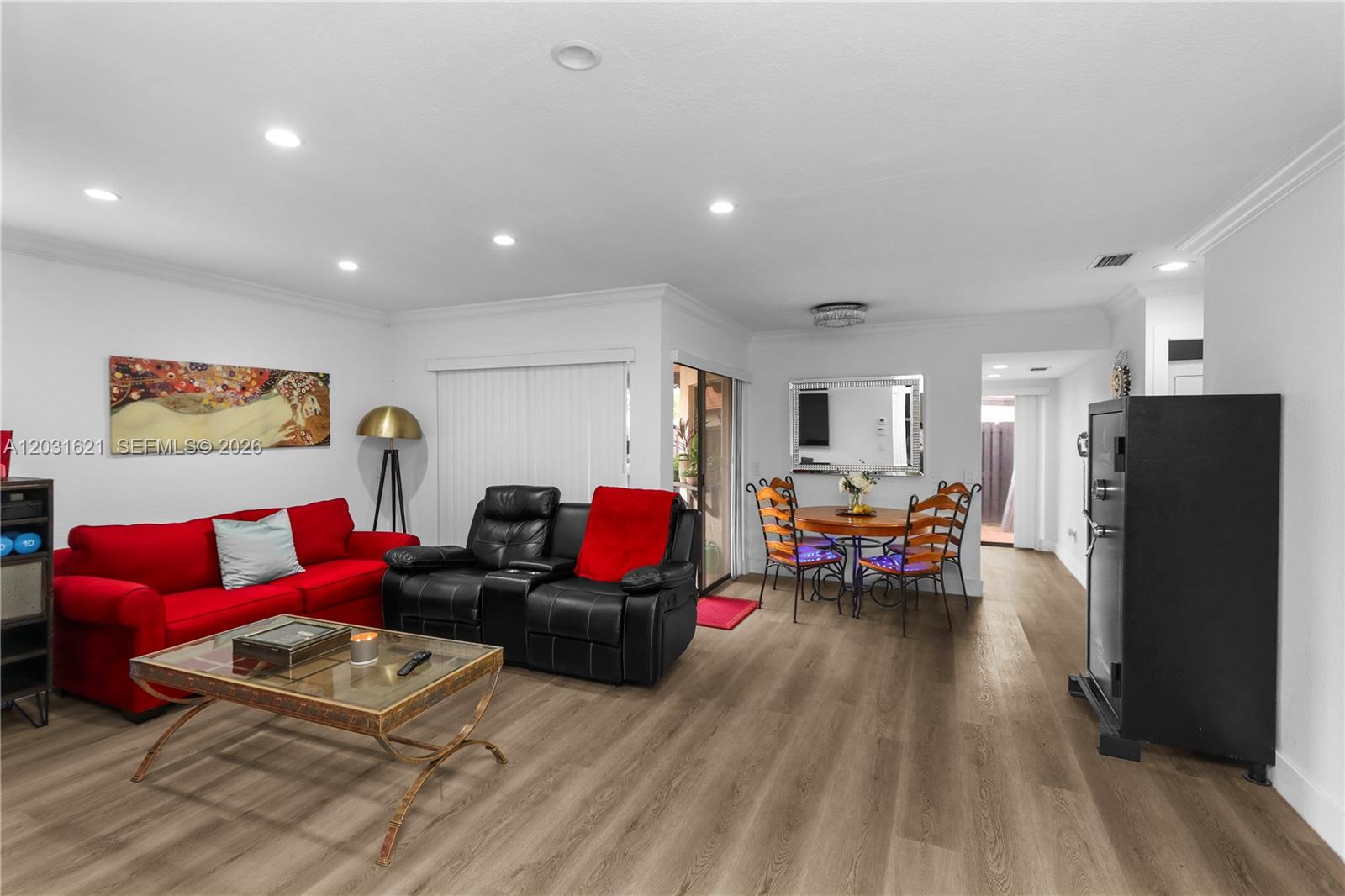 A living room and dining area feature wood-look flooring, a red sofa, and a black safe — 15240 SW 45th Ter # H, Miami FL 33185, MIAMI, FL