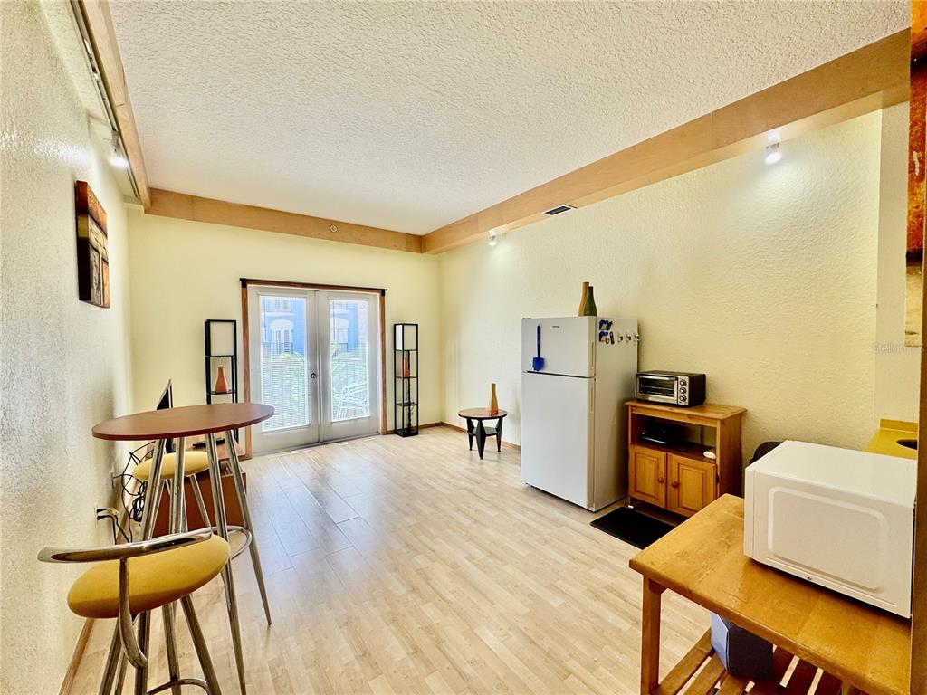 A kitchen and dining area with light wood flooring, a refrigerator, and a small table — 101 PALM HARBOR PARKWAY UNIT 228 B, PALM COAST, FL