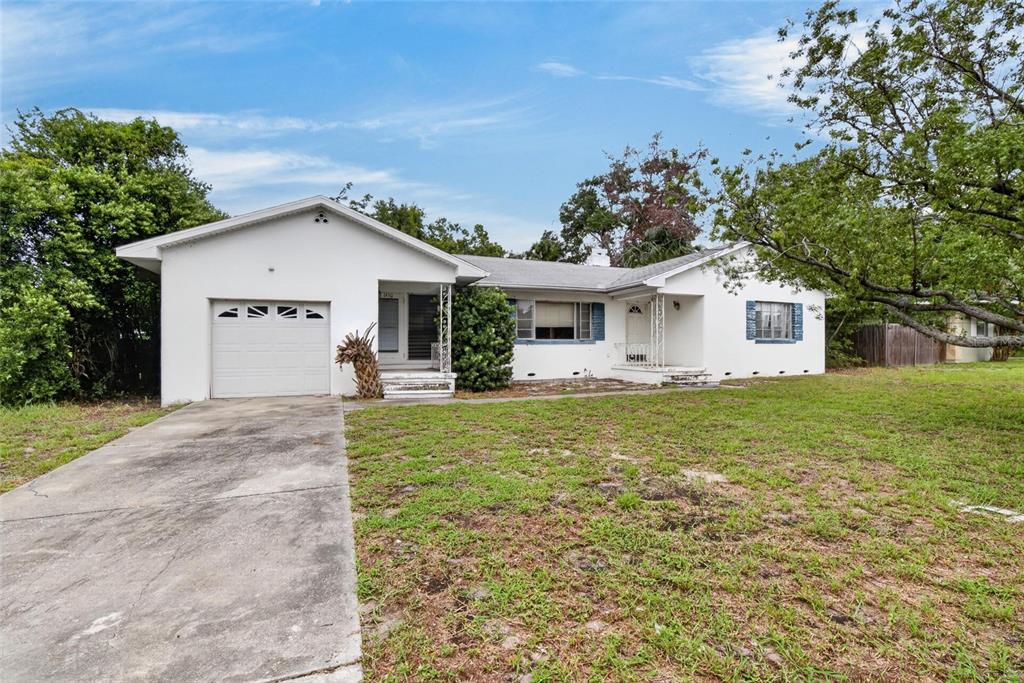 A white single-story house with a garage, concrete driveway, and a large front lawn — 1450 ROGERS STREET, CLEARWATER, FL