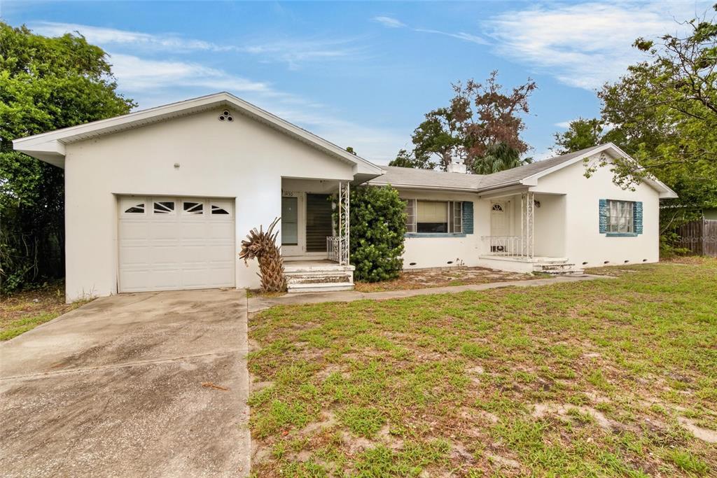 A single-story white house with a garage, a concrete driveway, and a grassy front yard — 1450 ROGERS STREET, CLEARWATER, FL