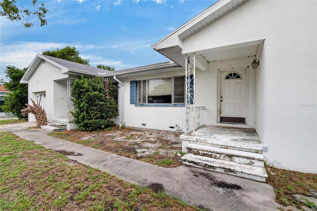 A white single-story house with a front porch, concrete steps, and a small yard — 1450 ROGERS STREET, CLEARWATER, FL