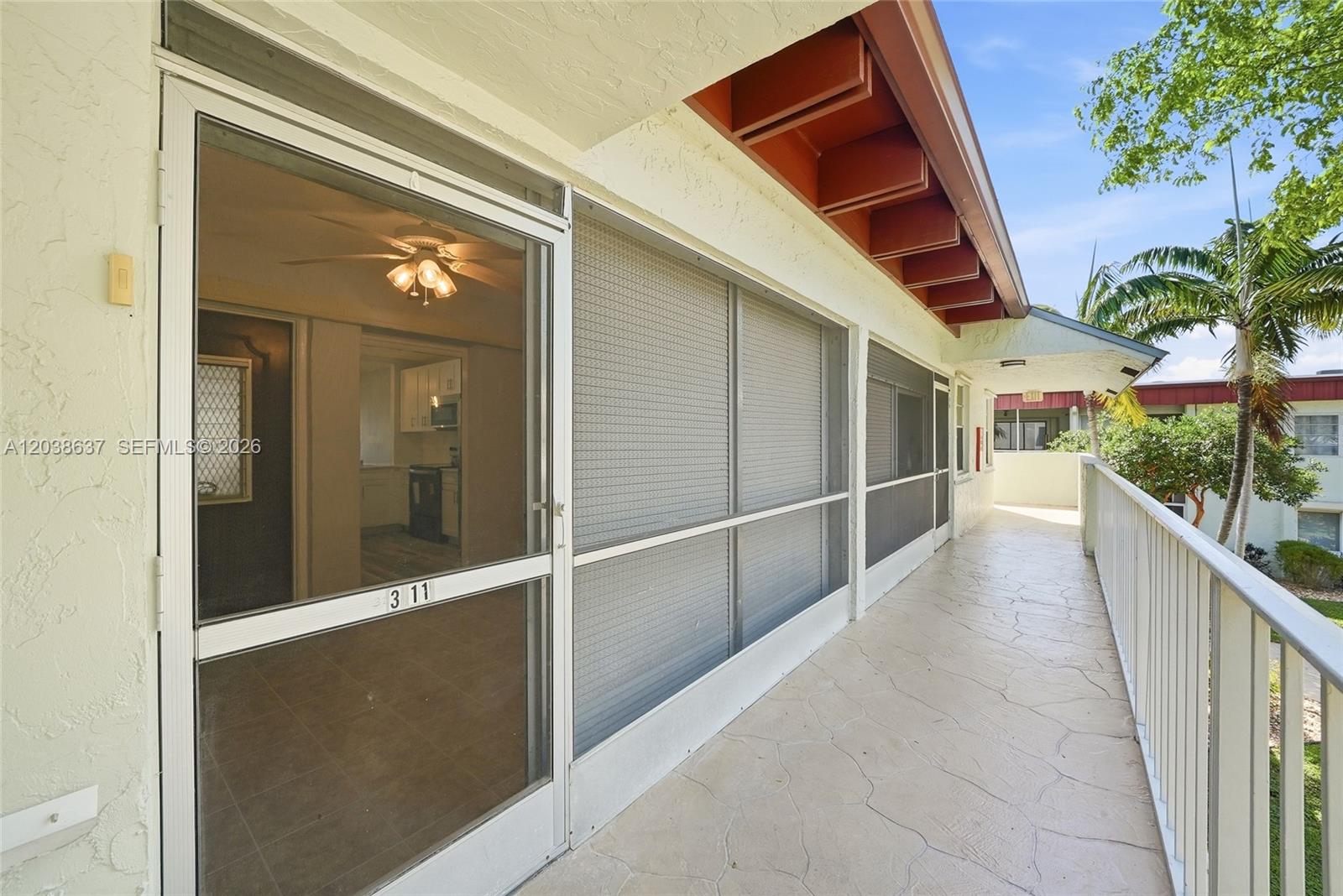 A screened-in balcony walkway features a white door labeled 311 and a metal railing — 860 SE 6 Ave # 311, Deerfield Beach FL 33441, DEERFIELD BEACH, FL