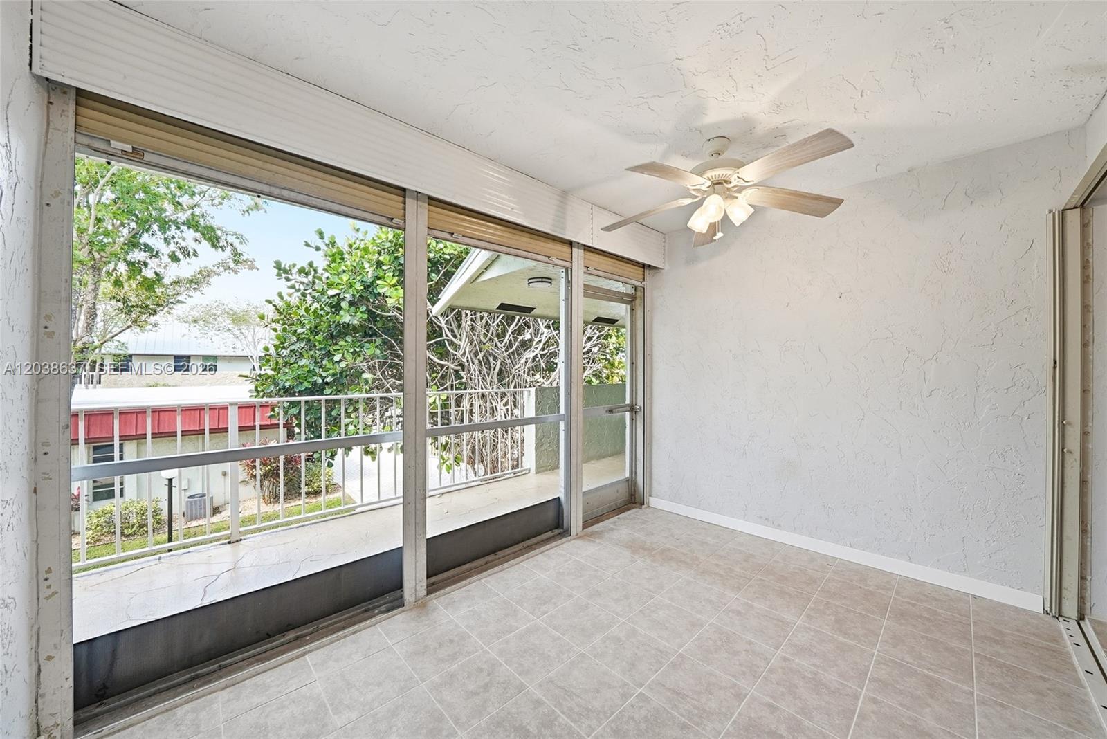 A sunroom with tile flooring, a ceiling fan, and sliding glass doors leading to a balcony — 860 SE 6 Ave # 311, Deerfield Beach FL 33441, DEERFIELD BEACH, FL