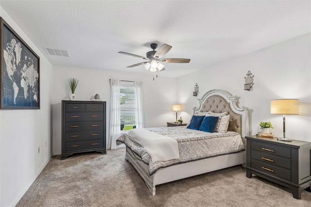 A bedroom features a bed with a tufted headboard, dark dressers, and a ceiling fan — 14334 HOLLY HAMMOCK LANE, BROOKSVILLE, FL