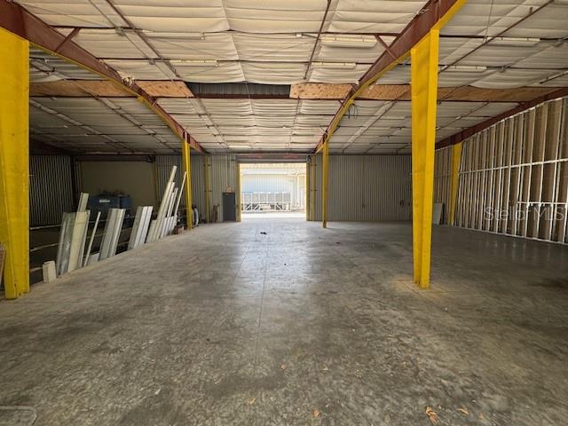 An empty warehouse interior features a concrete floor, yellow support beams, and metal walls — 2251 TOPLINE WAY UNIT 6, BROOKSVILLE, FL