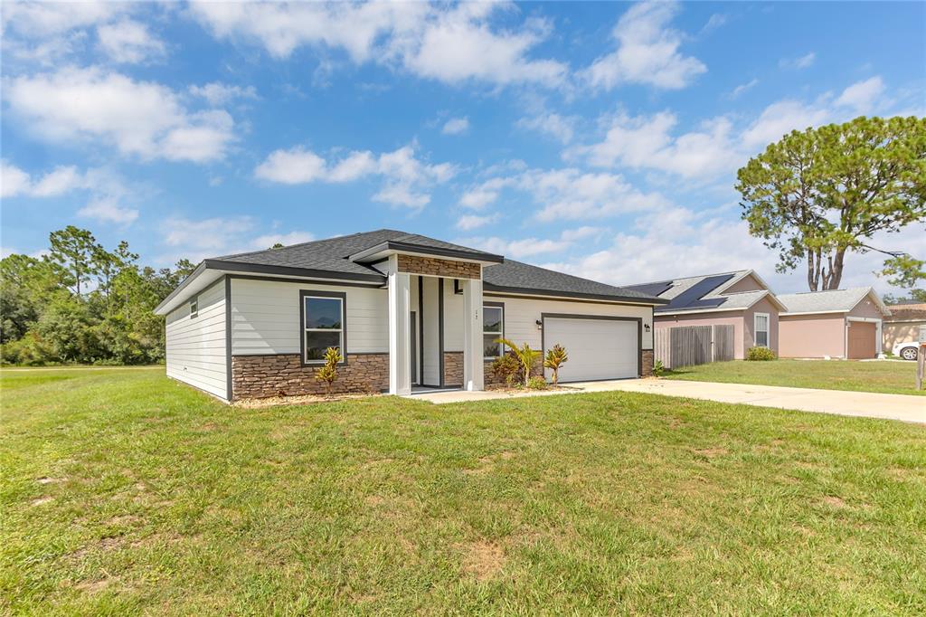 A single-story house with white siding, stone accents, a two-car garage, and a grassy yard — 17 HERRING COURT, KISSIMMEE, FL