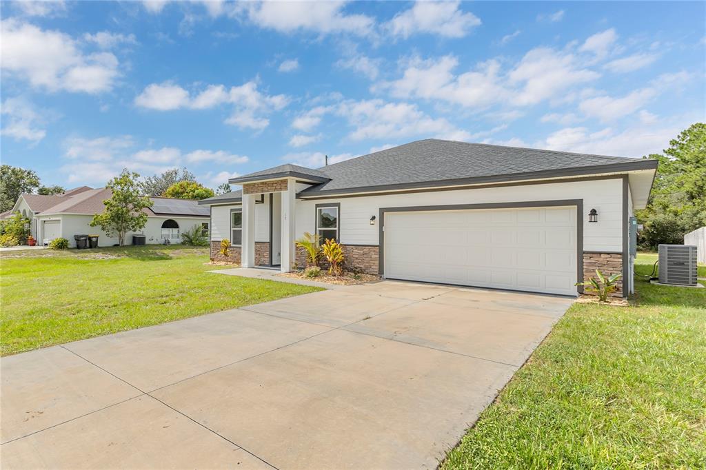A single-story house with a white exterior, stone accents, and a two-car garage — 17 HERRING COURT, KISSIMMEE, FL