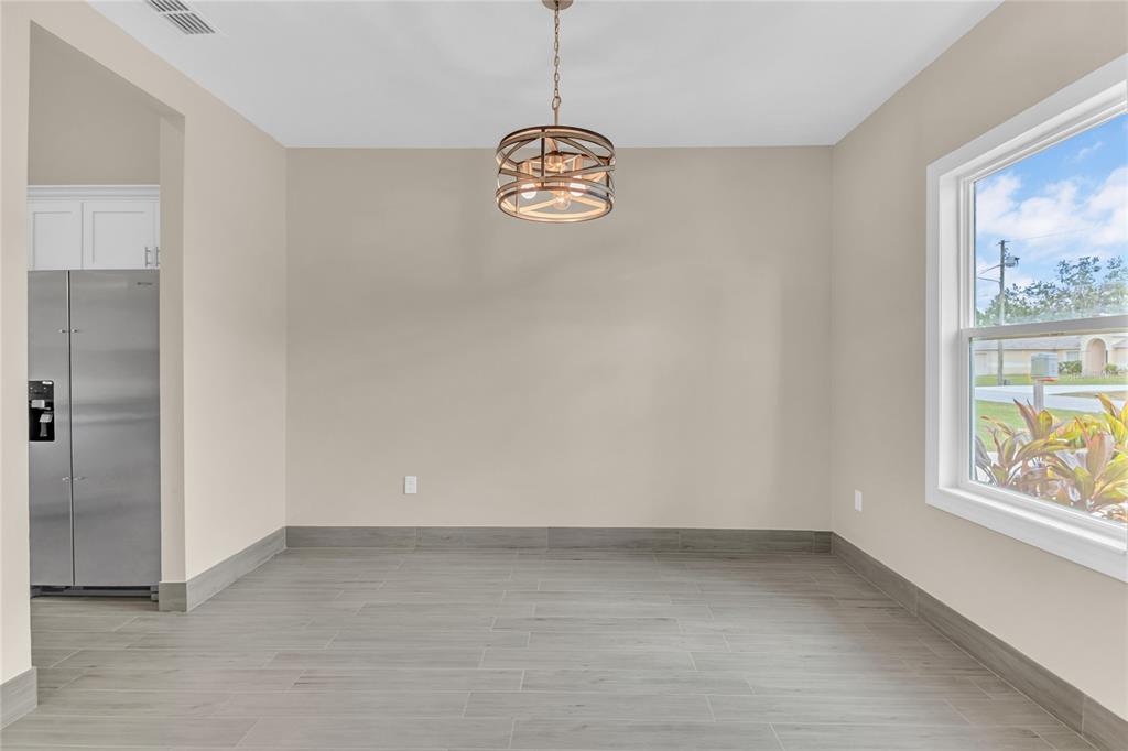 An empty dining area features light beige walls, wood-look tile flooring, and a drum pendant light — 17 HERRING COURT, KISSIMMEE, FL