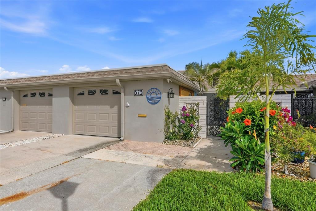 A single-story home exterior with a two-car garage, a decorative sun emblem, and landscaping — 573 BOCA CIEGA POINT BOULEVARD N, ST PETERSBURG, FL
