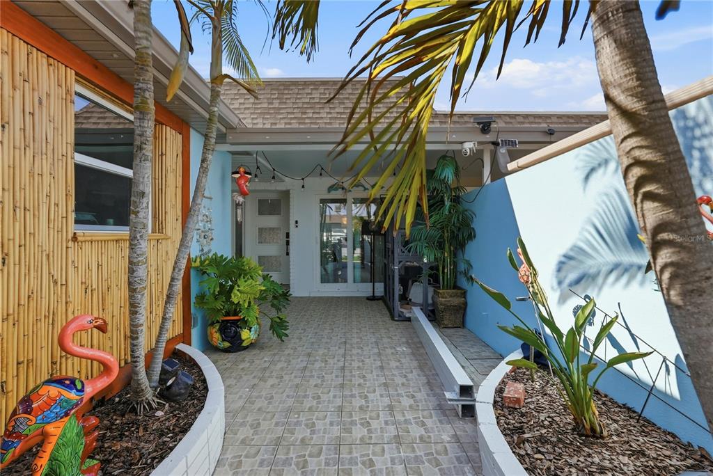 A tiled outdoor entryway features a bamboo-paneled wall, a blue wall, and potted plants — 573 BOCA CIEGA POINT BOULEVARD N, ST PETERSBURG, FL