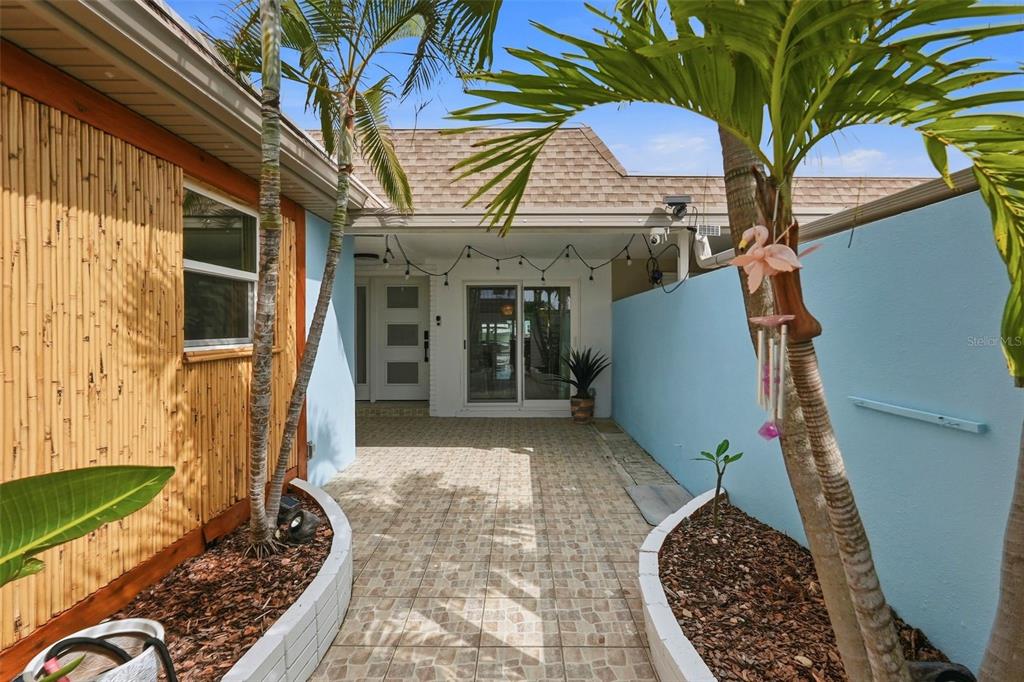 A paved patio area features light blue walls, bamboo siding, and two palm trees — 573 BOCA CIEGA POINT BOULEVARD N, ST PETERSBURG, FL