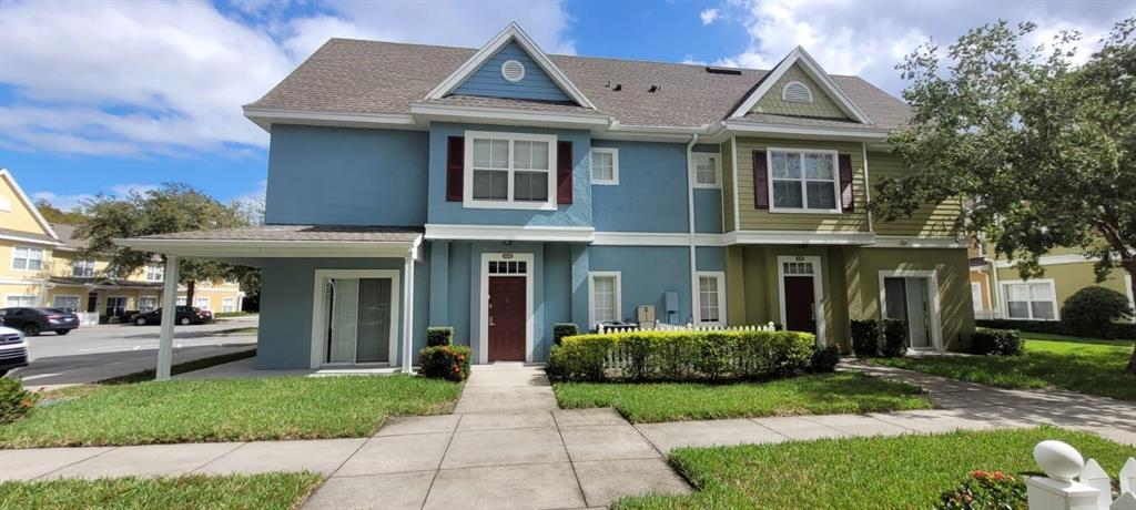 A two-story townhouse with blue and olive green siding and a covered front patio — 4004 SANTA MARIA DRIVE UNIT 101, KISSIMMEE, FL