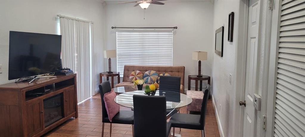 A living and dining area features a glass table, black chairs, and a brown sofa — 4004 SANTA MARIA DRIVE UNIT 101, KISSIMMEE, FL