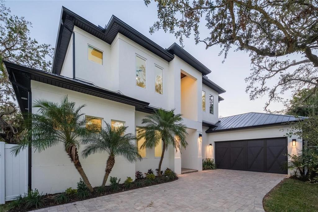 A two-story white house with a dark metal roof, palm trees, and a two-car garage — 2420 FLOYD STREET, SARASOTA, FL