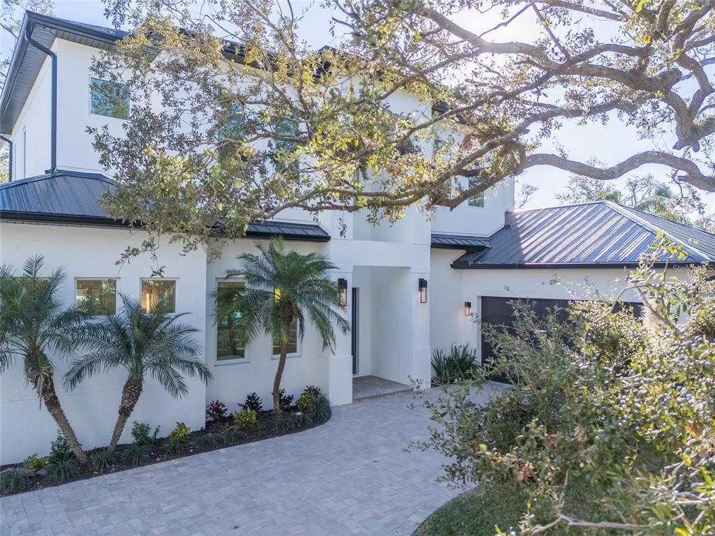 A two-story white house with a dark metal roof, palm trees, and a paved driveway — 2420 FLOYD STREET, SARASOTA, FL