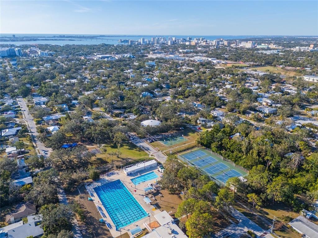 An aerial view shows a community swimming pool and tennis courts surrounded by residential homes — 2420 FLOYD STREET, SARASOTA, FL