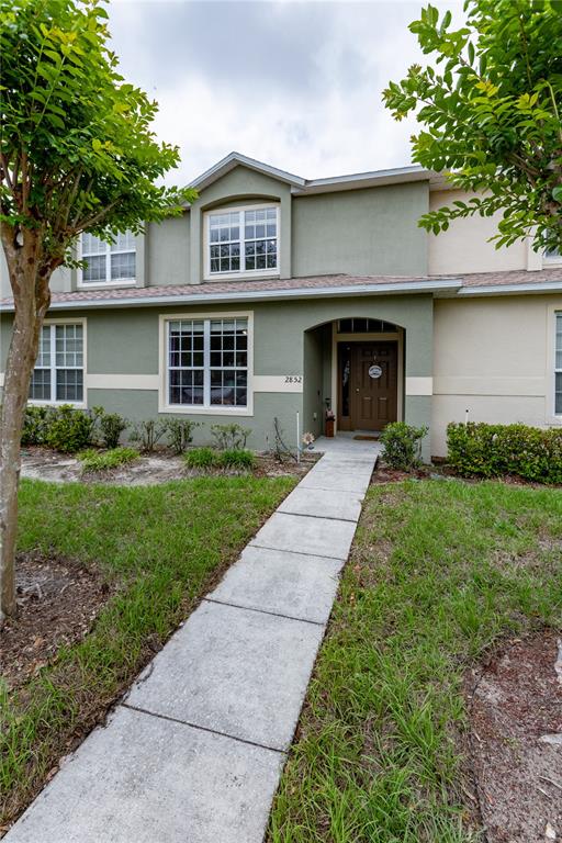 A two-story townhouse with a green exterior, a concrete walkway, and a brown front door — 2852 TANZANITE TERRACE, KISSIMMEE, FL