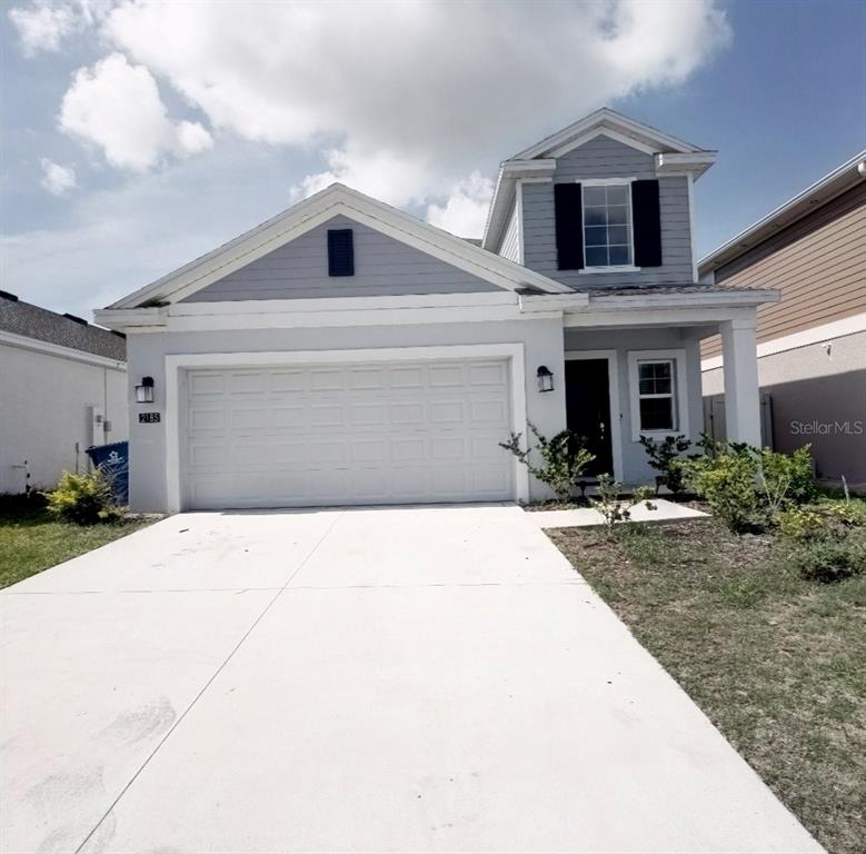A two-story house with a light gray exterior, a two-car garage, and a concrete driveway — 2185 AQUIFER LANE, DAVENPORT, FL