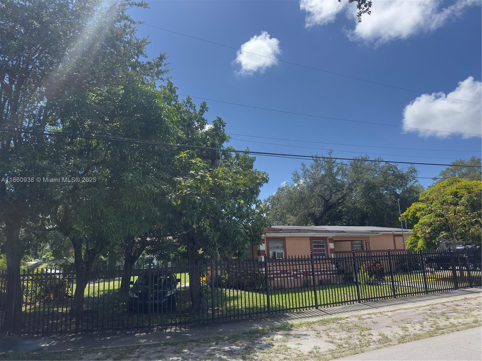 A single-story house with a tan exterior sits behind a black metal fence — 2490 NW 97th St # A, Miami FL 33147, MIAMI, FL