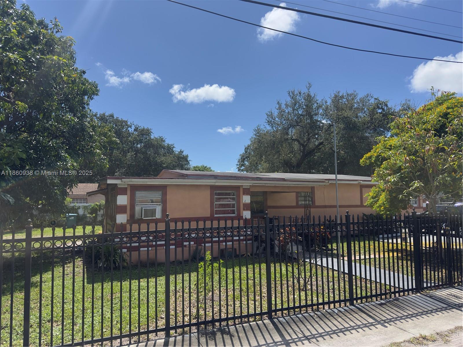 A single-story house with tan stucco walls and a black metal fence in the front yard — 2490 NW 97th St # A, Miami FL 33147, MIAMI, FL