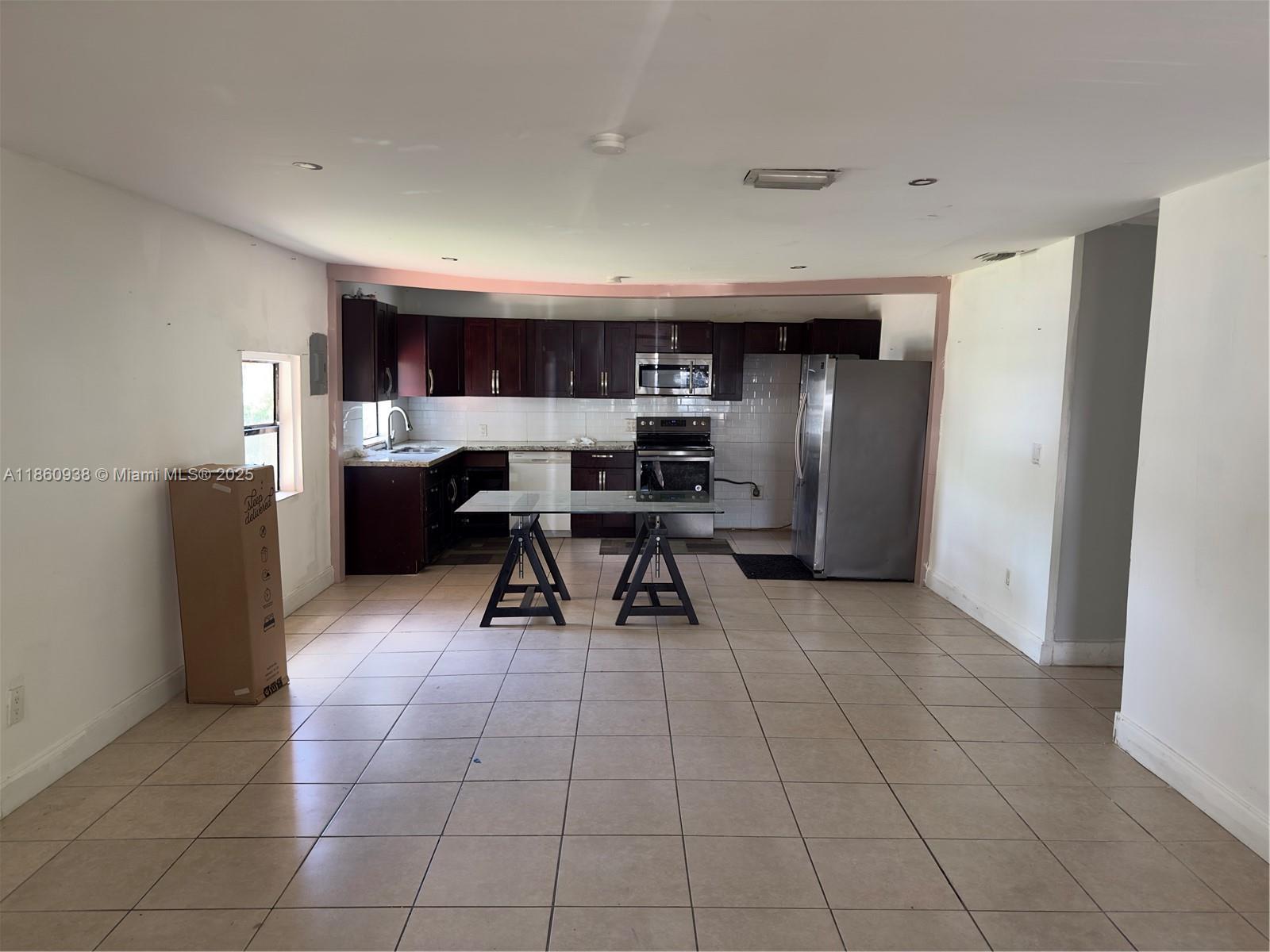 A kitchen features dark wood cabinets, stainless steel appliances, and a glass-topped table on sawhorses — 2490 NW 97th St # A, Miami FL 33147, MIAMI, FL