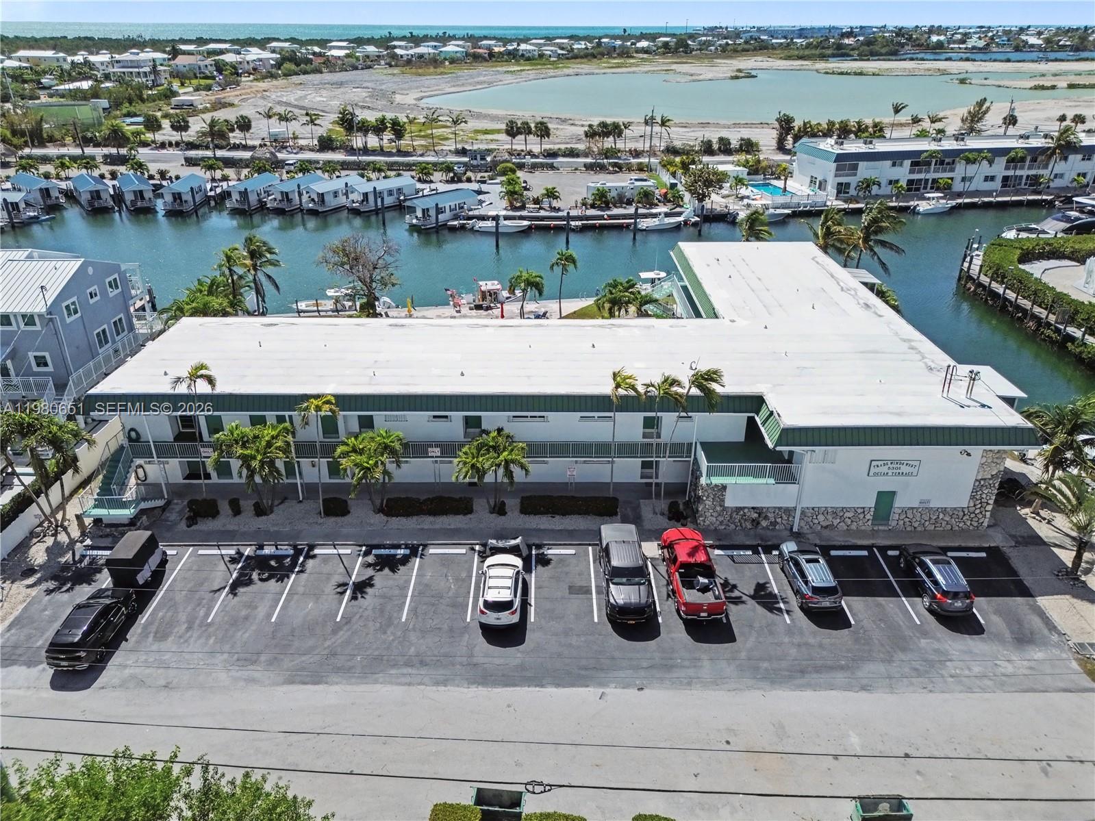 An aerial view shows a multi-story building with a parking lot and a boat dock — 5301 Ocean Ter # 7, Marathon FL 33050, MARATHON, FL