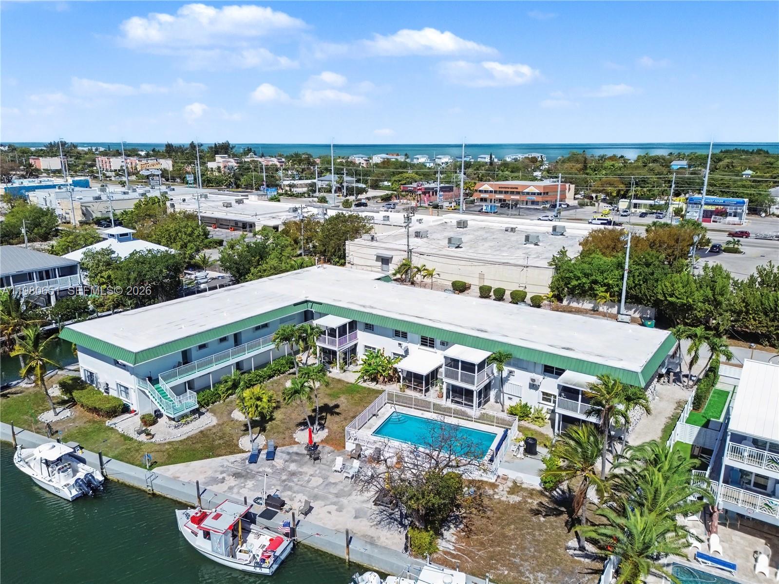 An aerial view shows a two-story apartment building with a pool and boat docks — 5301 Ocean Ter # 7, Marathon FL 33050, MARATHON, FL