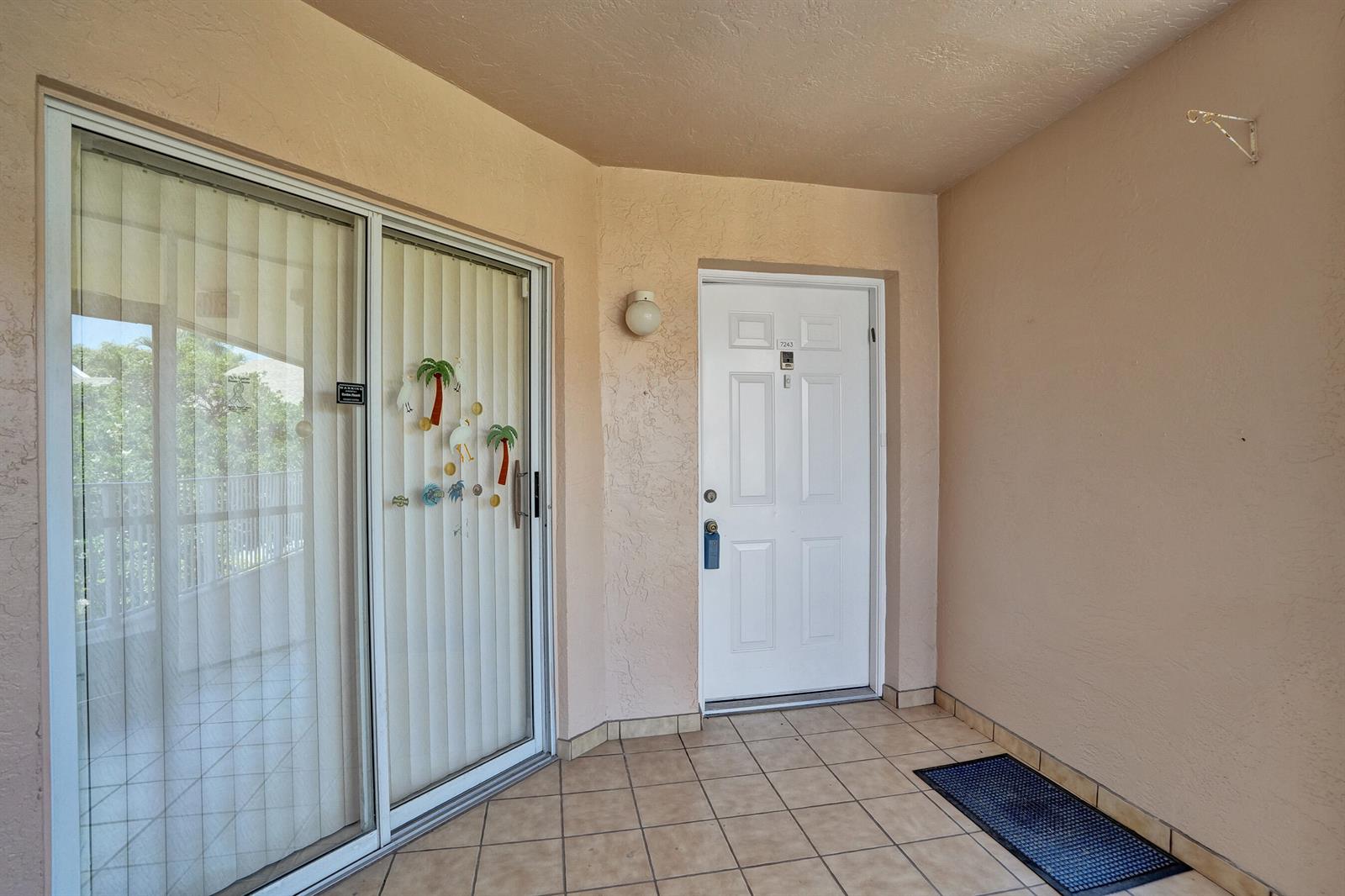 A tiled entryway features a white front door and a sliding glass door with blinds — 7243 S Devon Drive, Tamarac FL 33321, TAMARAC, FL