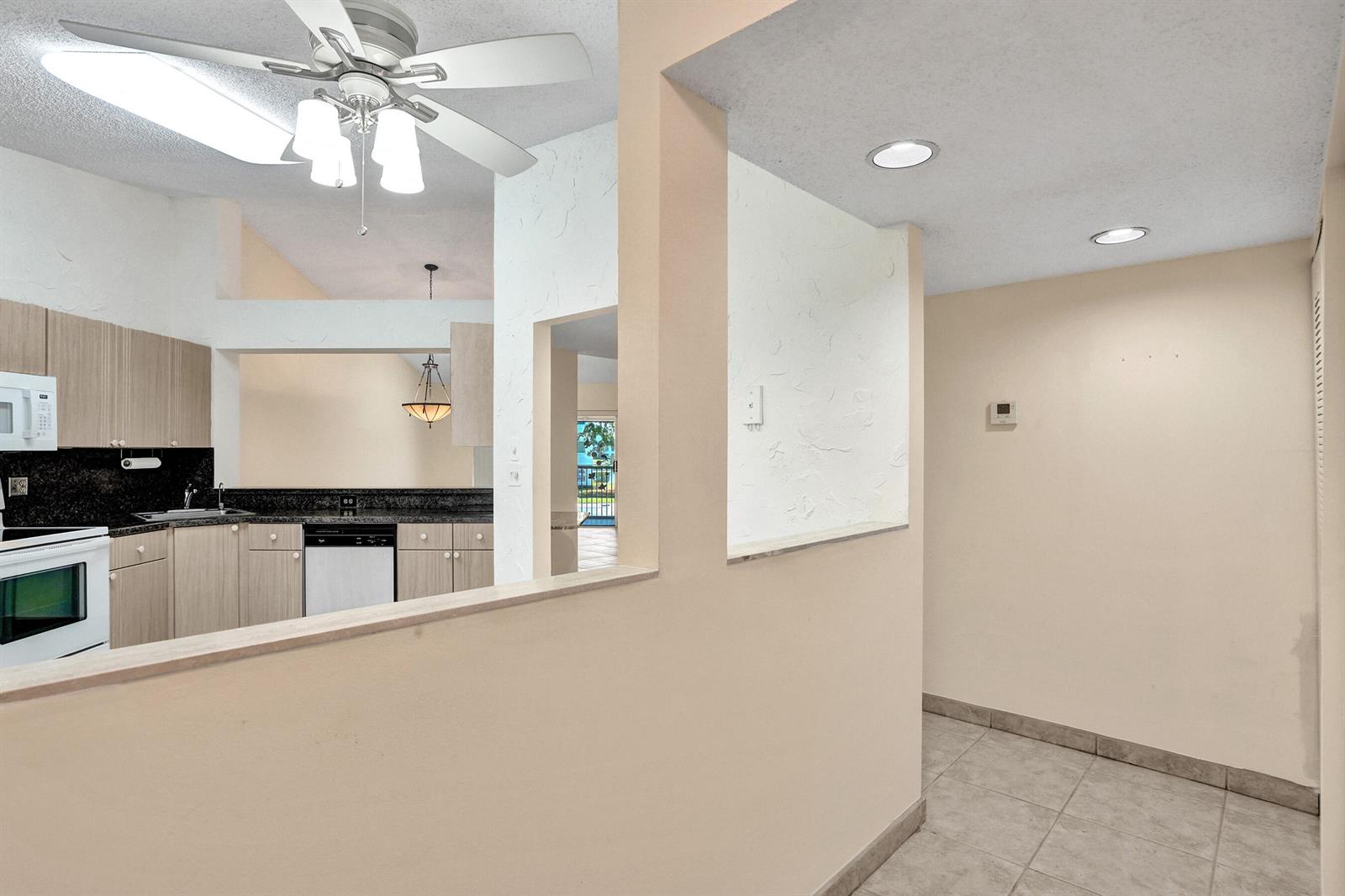A kitchen with light wood cabinets and granite countertops is visible through a wall opening — 7243 S Devon Drive, Tamarac FL 33321, TAMARAC, FL