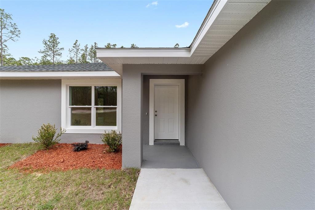 A gray exterior wall features a white front door and a window with white trim — 3598 SW 151ST COURT, OCALA, FL