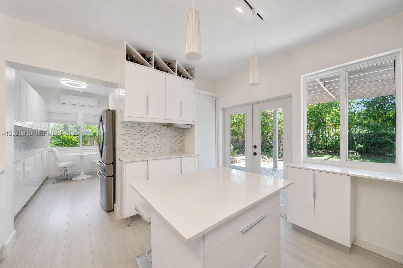 A bright kitchen features white cabinetry, a center island, and a view of the backyard — 860 NE 127TH ST, North Miami FL 33161, NORTH MIAMI, FL
