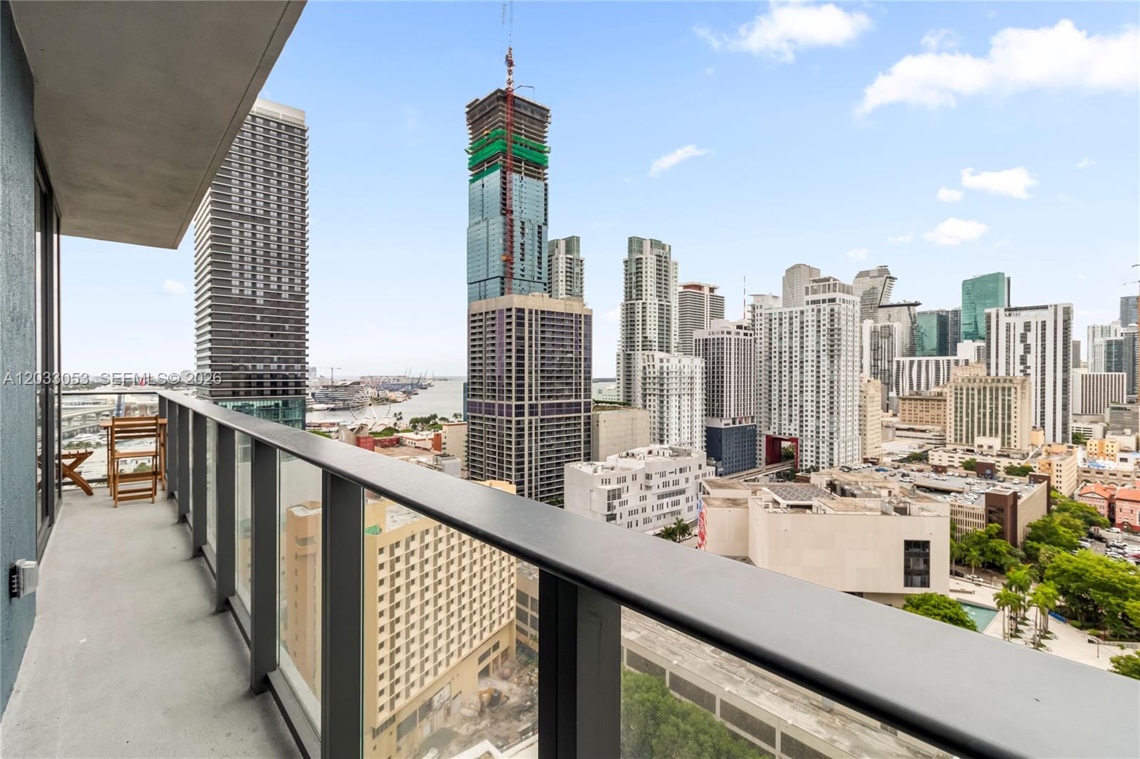 A balcony with a glass railing overlooks a dense city skyline and a harbor — 121 NE 5th St # 2401, Miami FL 33132, MIAMI, FL