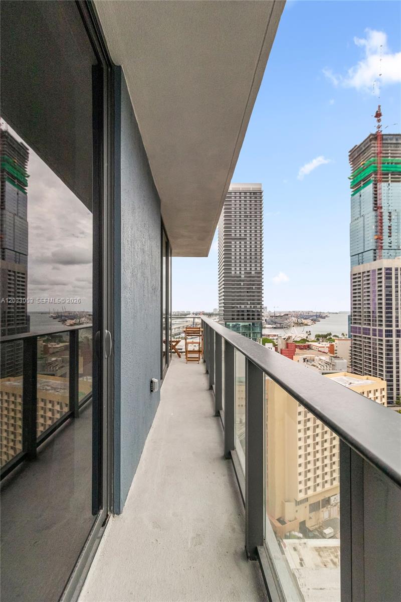A balcony with a glass railing overlooks a city skyline and a harbor — 121 NE 5th St # 2401, Miami FL 33132, MIAMI, FL