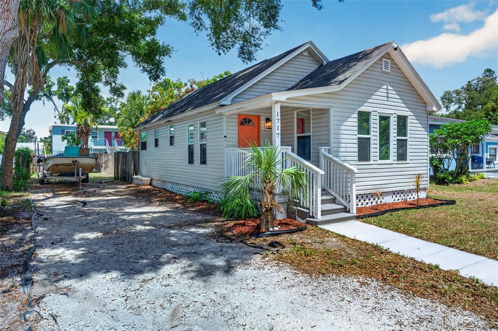 A light gray, single-story house with a bright orange front door and a gravel driveway — 1717 18TH STREET S, ST PETERSBURG, FL
