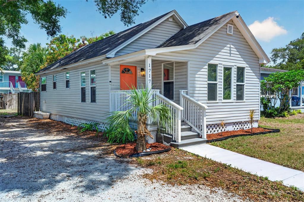 A light gray, single-story house with a bright orange front door and white porch railings — 1717 18TH STREET S, ST PETERSBURG, FL
