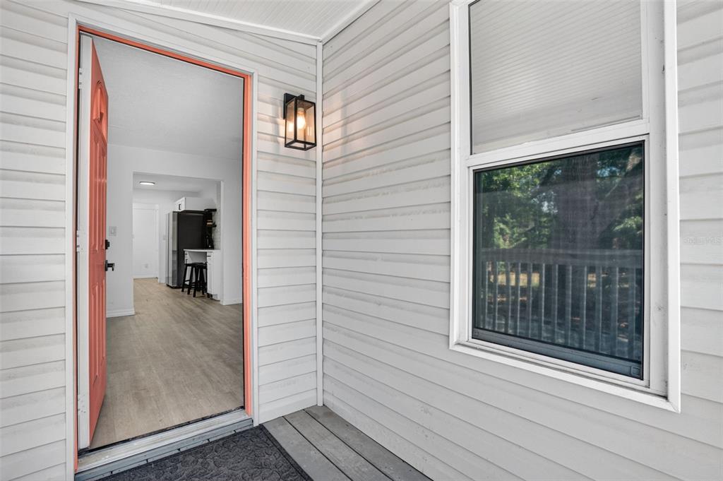 An open door reveals a kitchen interior from a light-gray vinyl-sided exterior porch — 1717 18TH STREET S, ST PETERSBURG, FL