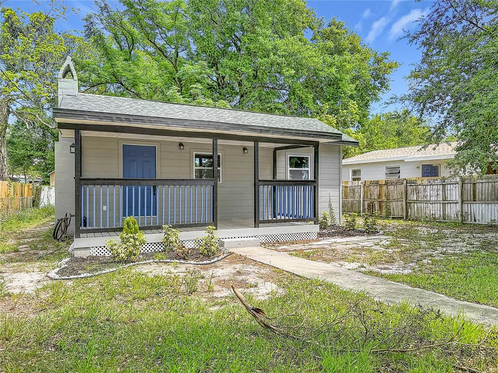 A small, gray, single-story house with a front porch, blue door, and a fenced yard — 9219 N 13TH STREET, TAMPA, FL