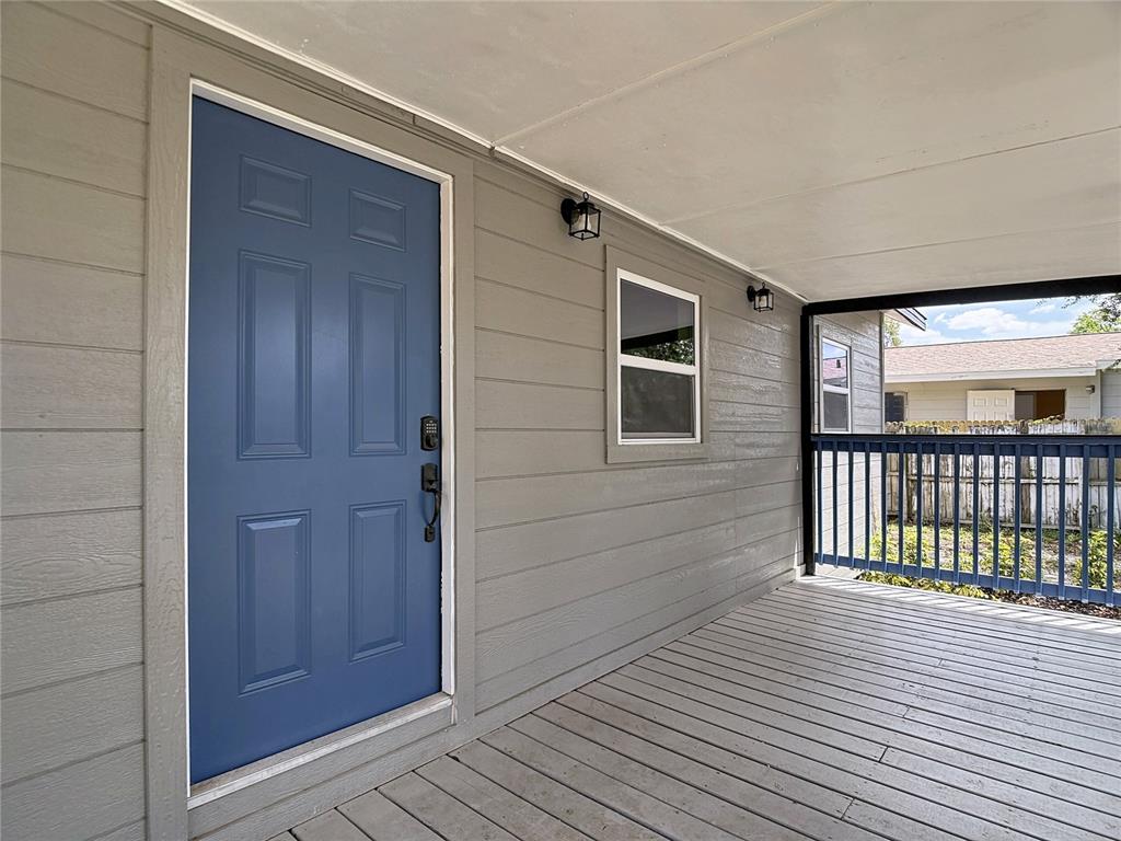 A blue front door opens onto a covered wooden porch with gray siding — 9219 N 13TH STREET, TAMPA, FL