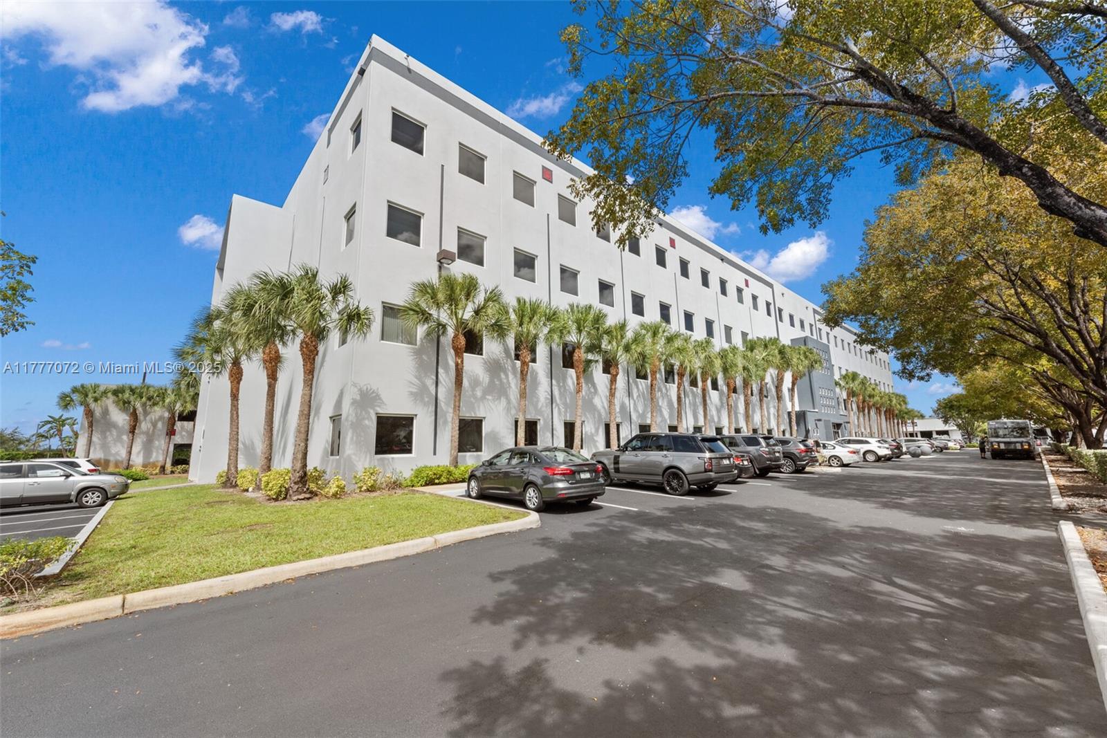 A multi-story office building features a parking lot with palm trees and several parked cars — 7791 NW 46th St # 215, Doral FL 33166, DORAL, FL