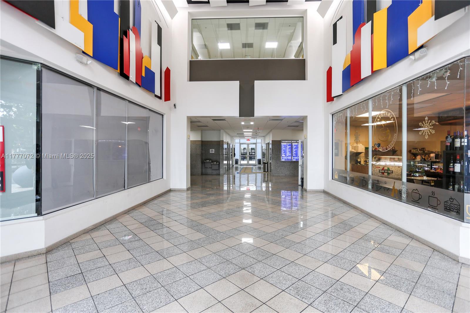 A bright, tiled hallway features glass-walled storefronts, geometric wall art, and a central corridor — 7791 NW 46th St # 215, Doral FL 33166, DORAL, FL