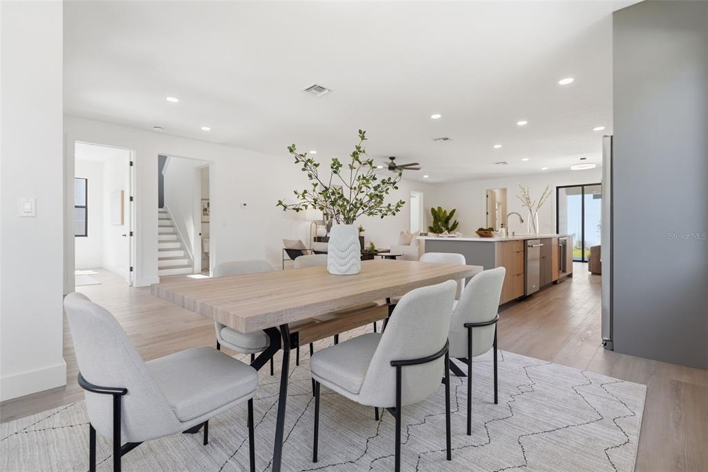 A dining area with a wooden table and light gray chairs sits before an open kitchen — 3516 21ST AVENUE S, ST PETERSBURG, FL