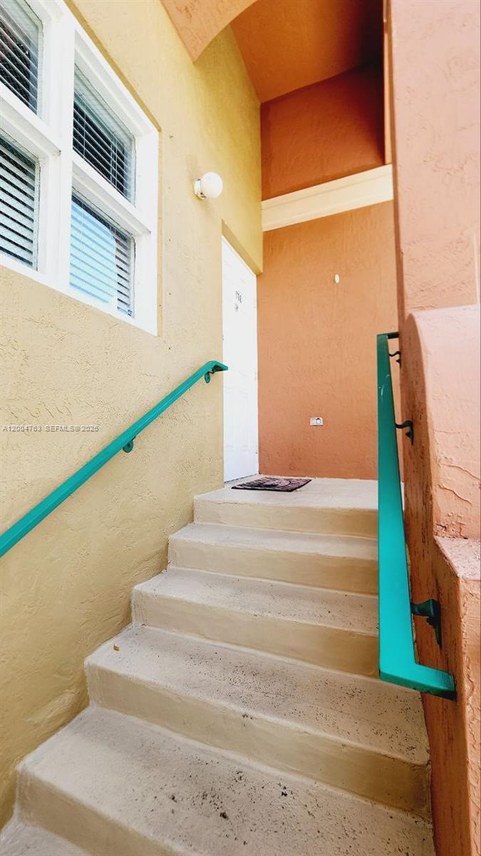 A set of concrete stairs leads to a white door between yellow and orange walls — 6960 NW 174th Ter # 706, Hialeah FL 33015, HIALEAH, FL