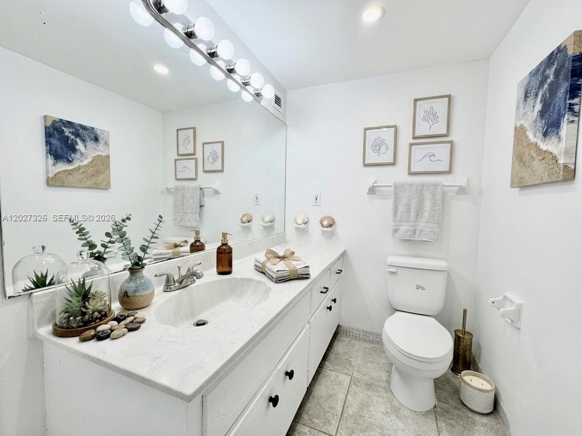 A bathroom features a white vanity with a marble countertop, a large mirror, and toilet — 800 West Ave # 924, Miami Beach FL 33139, MIAMI BEACH, FL