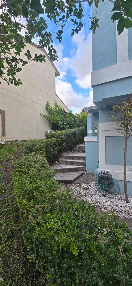 A stone staircase leads between two residential buildings past a manicured hedge and garden — 10001 SW 218th St, Cutler Bay FL 33190, CUTLER BAY, FL