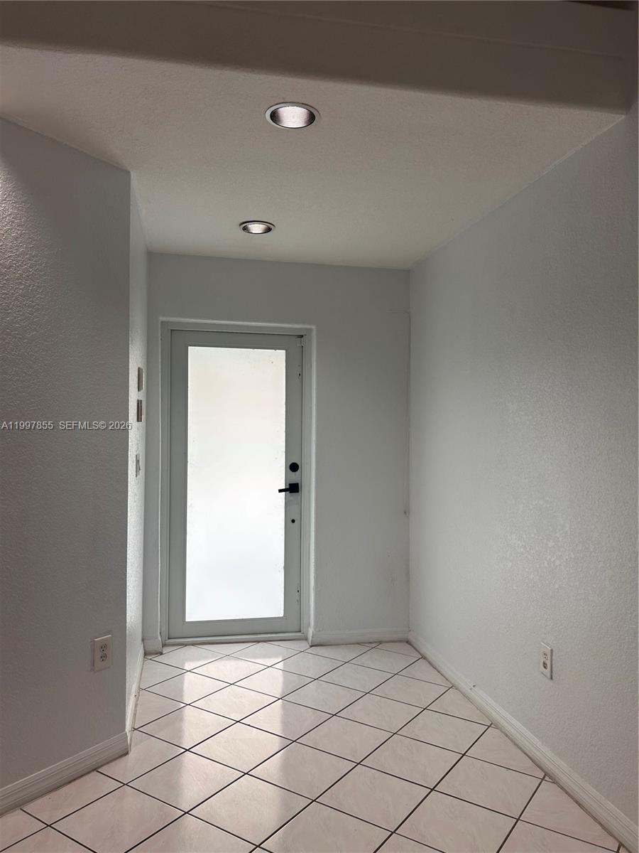 An entryway features white walls, a tiled floor, and a glass-paneled door with recessed lighting — 10001 SW 218th St, Cutler Bay FL 33190, CUTLER BAY, FL