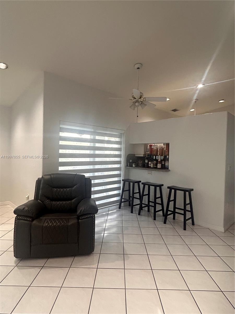 A living area features white tile floors, a dark leather recliner, and a breakfast bar — 10001 SW 218th St, Cutler Bay FL 33190, CUTLER BAY, FL