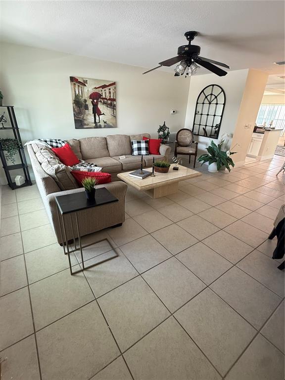 A living room features a beige sectional sofa, a coffee table, and tile flooring — 9021 41ST WAY N UNIT 0, PINELLAS PARK, FL