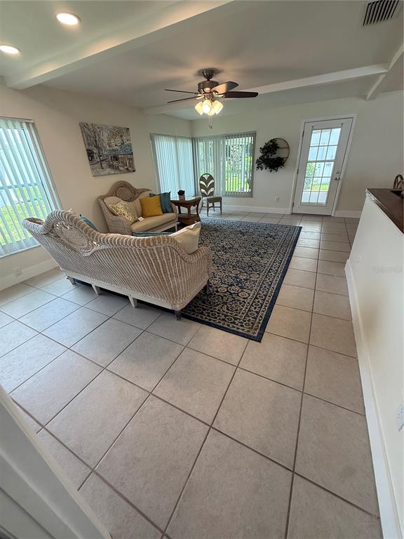 A living room features tiled floors, wicker furniture, a large area rug, and ceiling lighting — 9021 41ST WAY N UNIT 0, PINELLAS PARK, FL